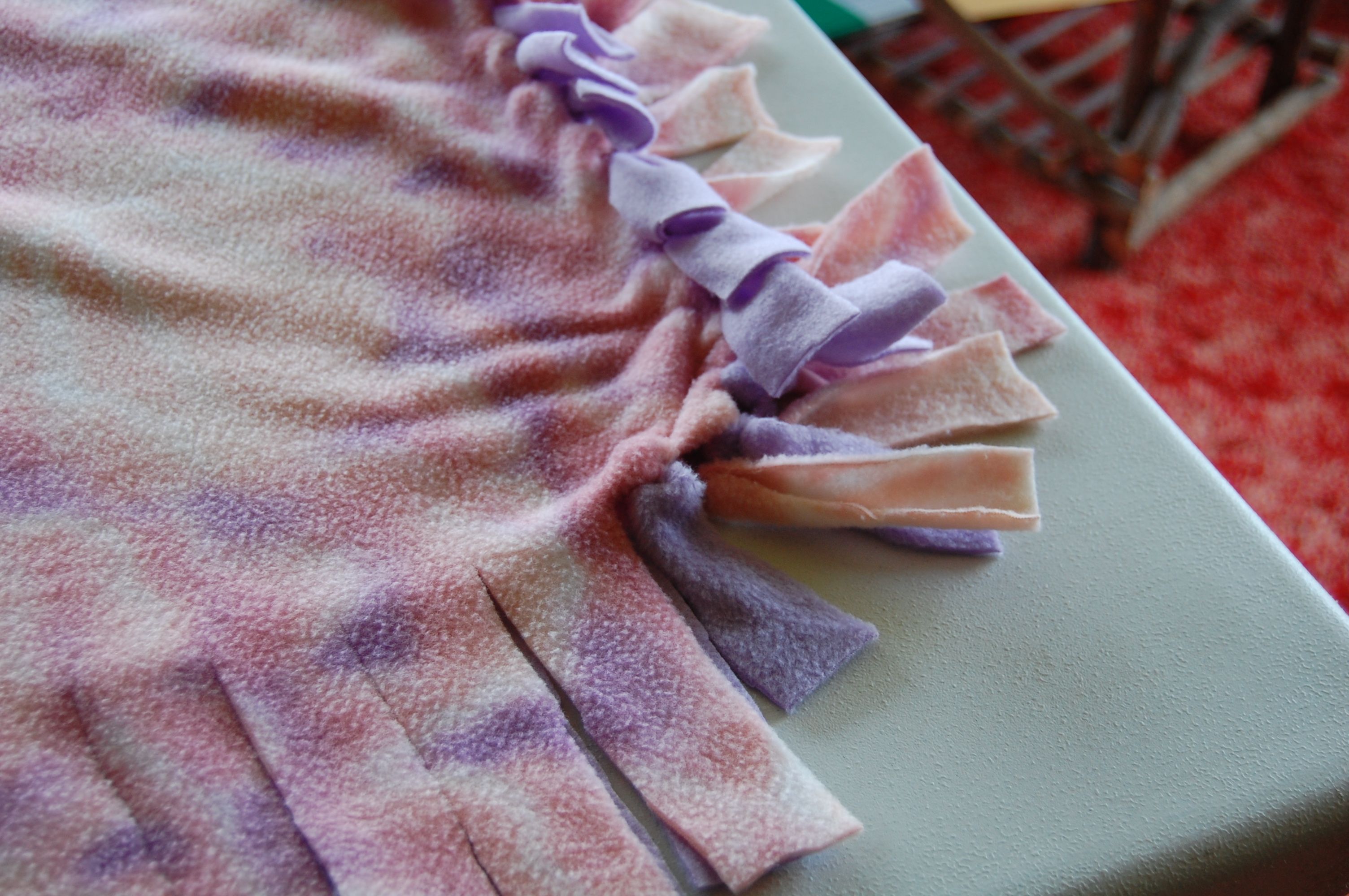 A fringed fleece blanket made from two pieces of fleece attached together. 